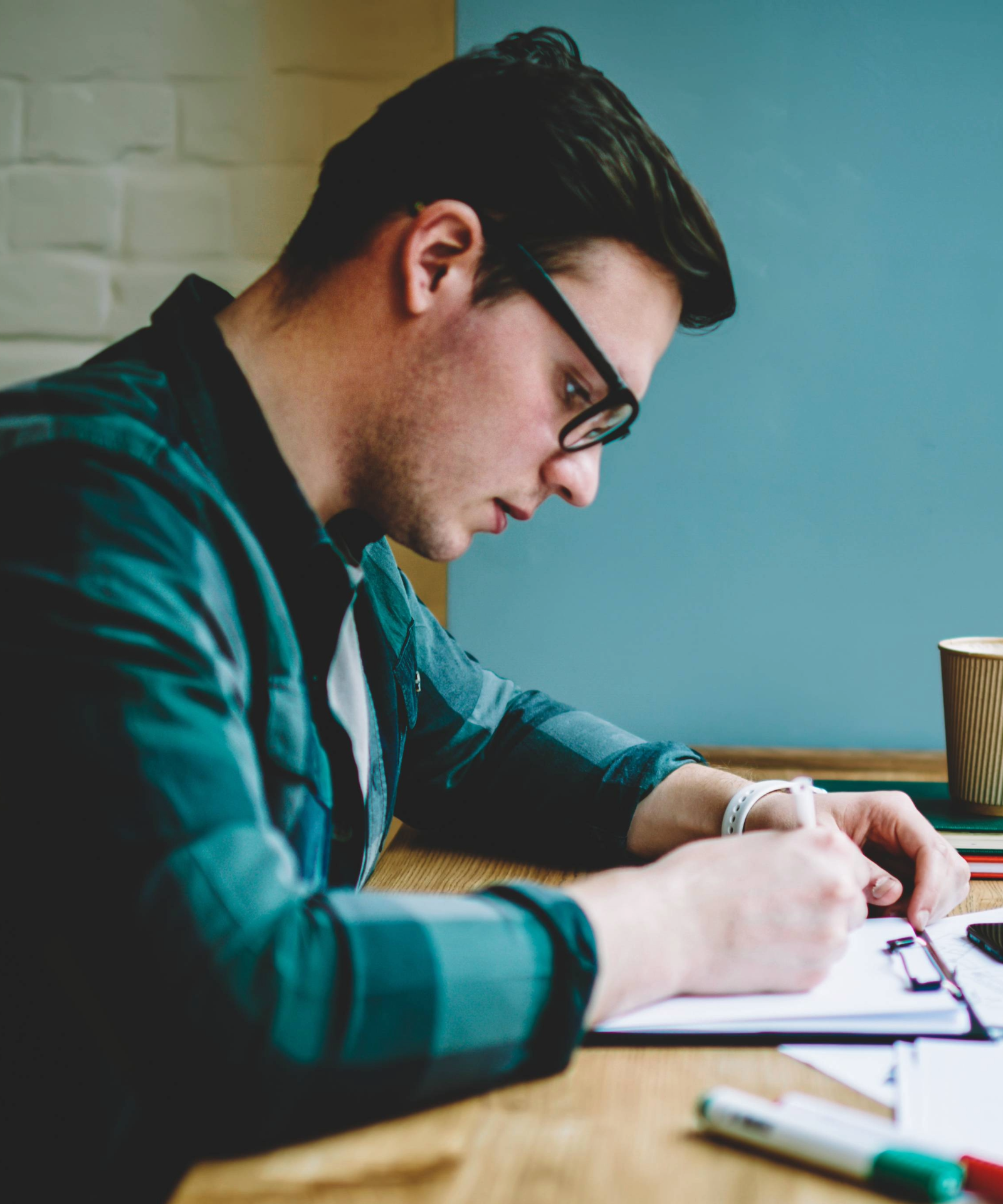 Man in glasses writing on a clipboard