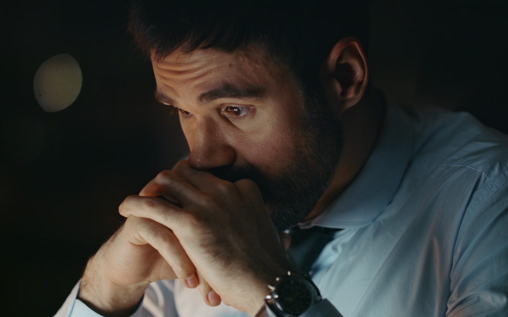 A man looking intensely focused and stressed with his hands clasped to his face